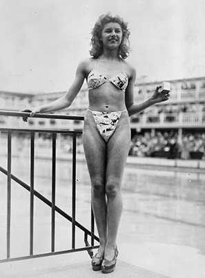 Sobre bikinis, aliens, astronautas, gênios e explosões atômicas The new 'Bikini' swimming costume (in a newsprint-patterned fabric), which caused a sensation at a beauty contest at the Molitor swimming pool in Paris. Designer Louis Reard was unable to find a 'respectable' model for his costume and the job of displaying it went to 19-year-old Micheline Bernardini, a nude dancer from the Casino de Paris. She is holding a small box into which the entire costume can be packed. Celebrated as the first bikini, Luard's design came a few months after a similar two-piece design was produced by French designer Jacques Heim. (Photo by Keystone/Getty Images)